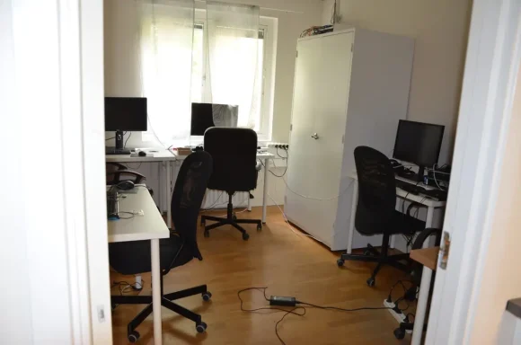 Ljust kontorsutrymme med flera datorer och kontorsstolar.